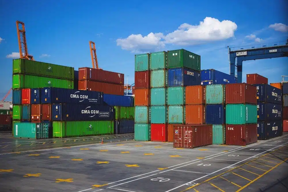 Colorful shipping containers stacked in organized rows at busy cargo yard terminal