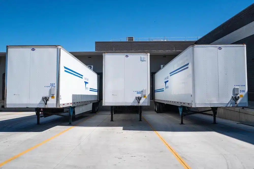 Three white semi-trailers parked at loading dock bays for yard management operations
