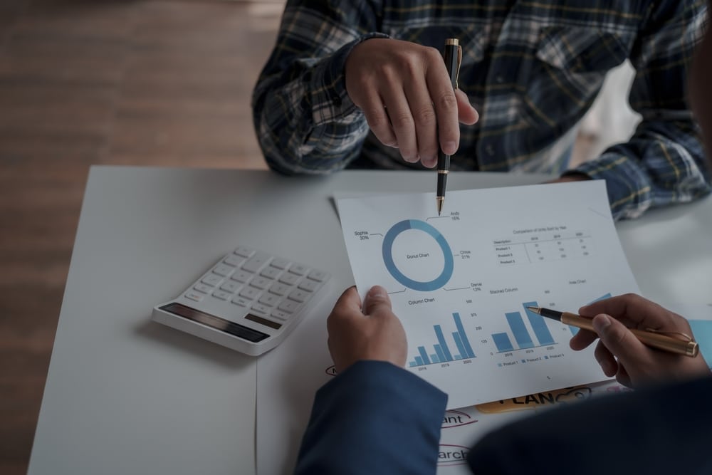 warehouse managers viewing inventory turnover ratio chart paper